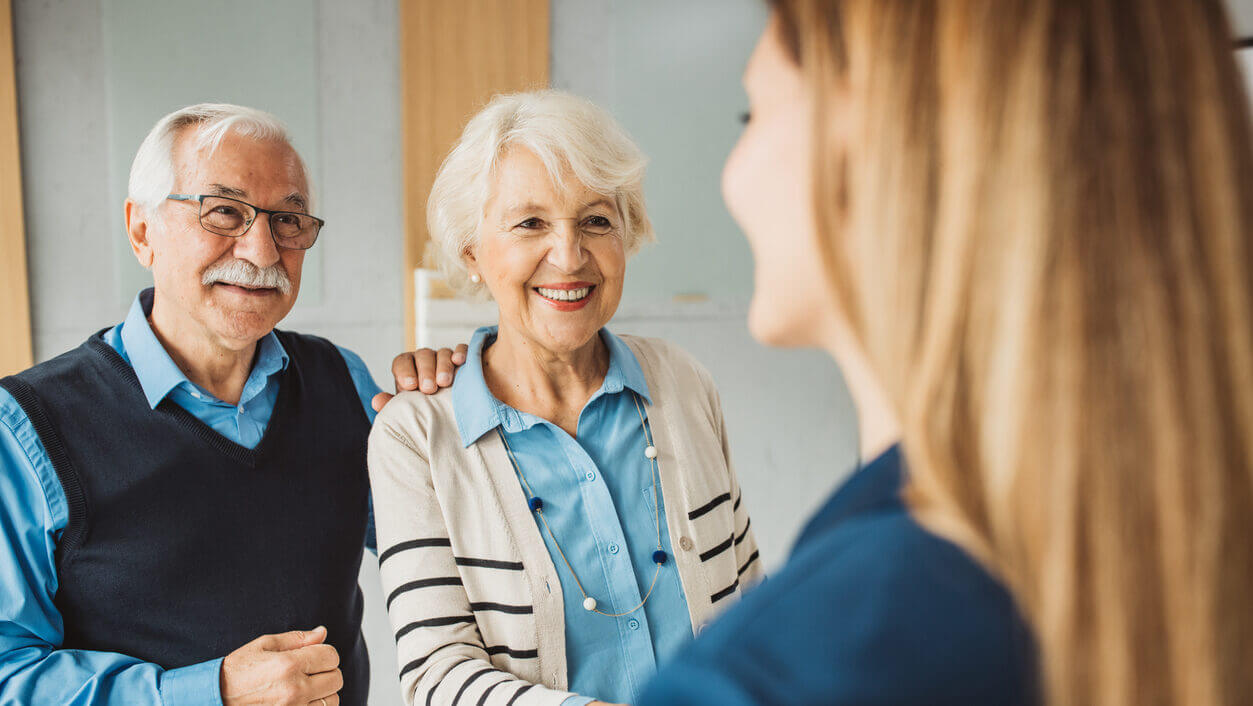 Senior couple talking with female financial or real estate advisor at her office.