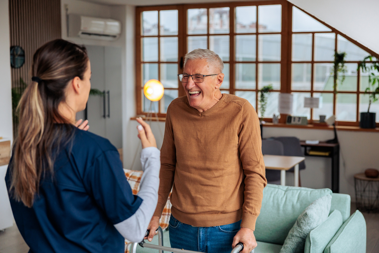 Caring nurse providing support to an smiling senior man