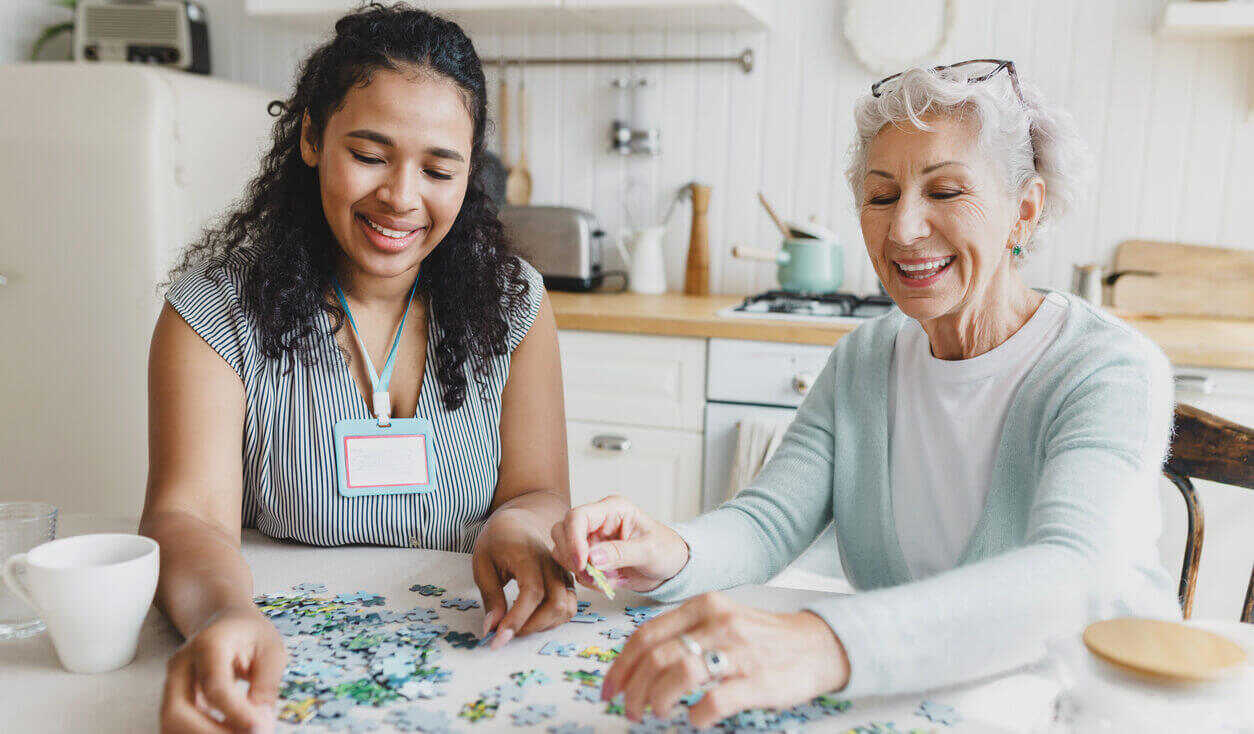 young female volunteer and older woman working on a puzzle.
